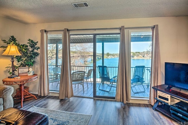 doorway to outside featuring a water view, dark hardwood / wood-style floors, and a textured ceiling