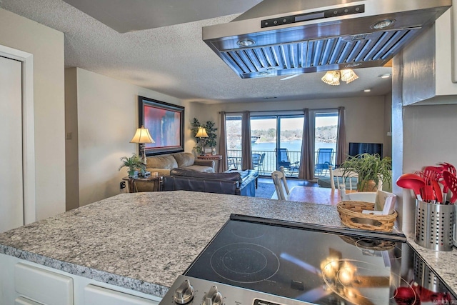 kitchen featuring white cabinets, stovetop, a water view, and a textured ceiling