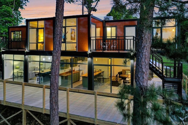 back house at dusk featuring a deck