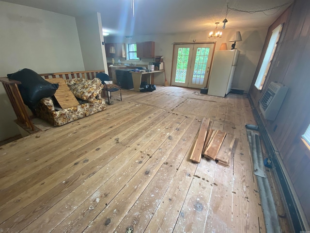 unfurnished living room with hardwood / wood-style flooring, an inviting chandelier, and french doors