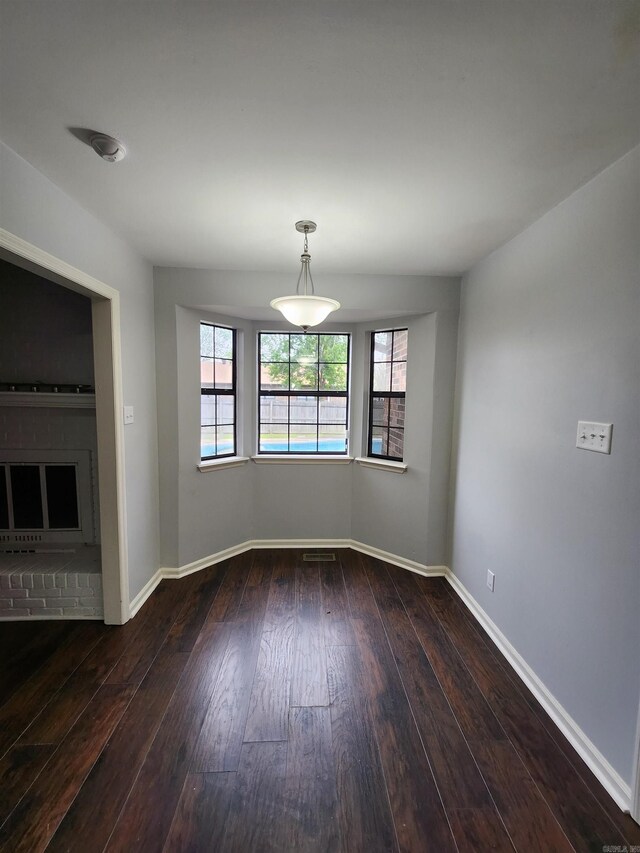 spare room featuring wood-type flooring and a fireplace