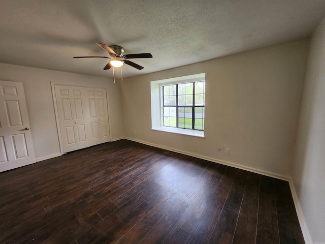 spare room featuring dark hardwood / wood-style flooring, ceiling fan, and a textured ceiling