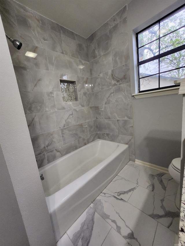 bathroom featuring toilet, tiled shower / bath, and tile flooring