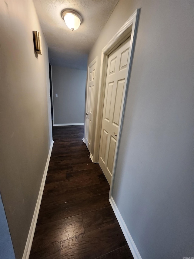 hallway with dark hardwood / wood-style flooring and a textured ceiling