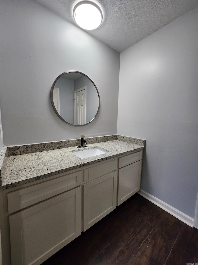 bathroom with wood-type flooring, large vanity, and a textured ceiling