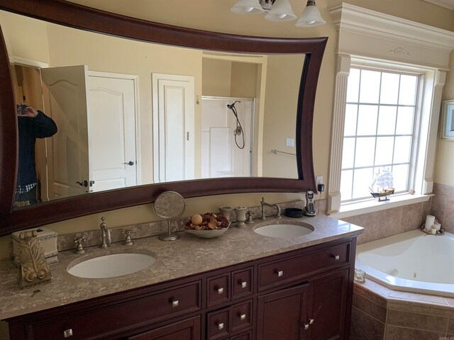 bathroom featuring a wealth of natural light, dual vanity, and tiled bath