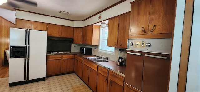 kitchen featuring white fridge with ice dispenser, light tile floors, cooktop, sink, and crown molding