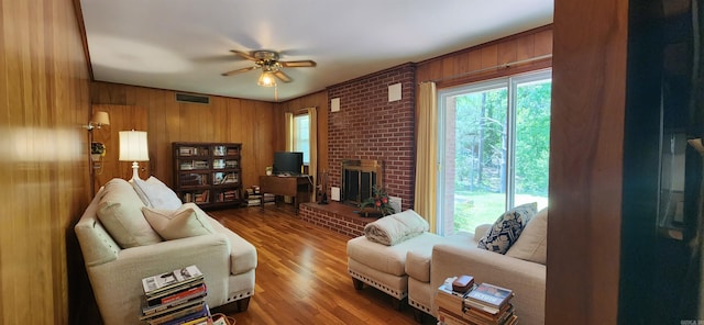 living room with wood-type flooring, ceiling fan, a fireplace, and wood walls