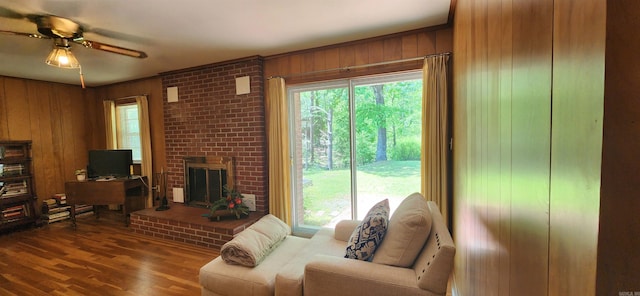 living room with wooden walls, plenty of natural light, ceiling fan, and hardwood / wood-style floors