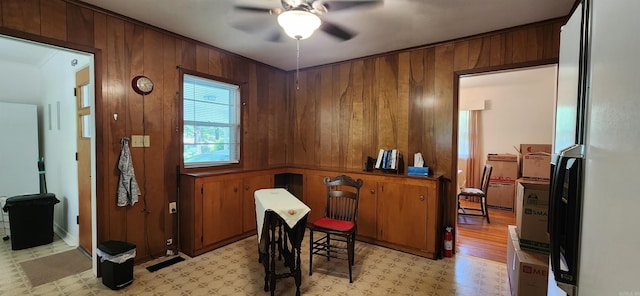 office space with wooden walls, ceiling fan, and light tile floors