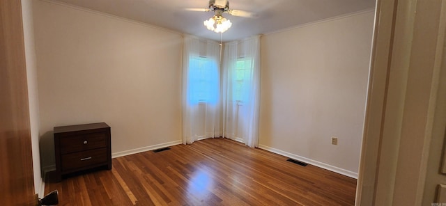 empty room featuring ornamental molding, ceiling fan, and dark wood-type flooring