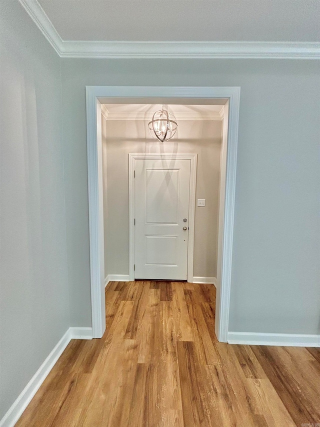 doorway with an inviting chandelier, ornamental molding, and light wood-type flooring