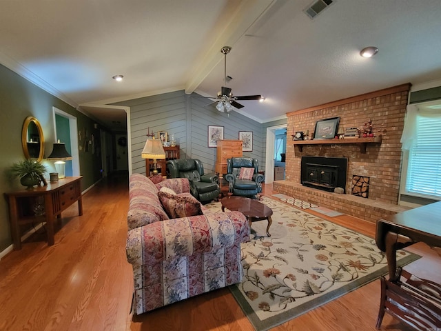 living room featuring a fireplace, crown molding, ceiling fan, and vaulted ceiling with beams