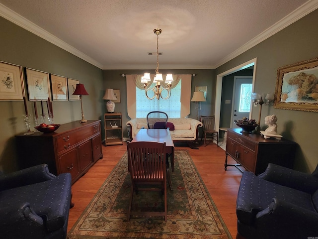 dining room featuring crown molding, a textured ceiling, hardwood / wood-style flooring, and a notable chandelier