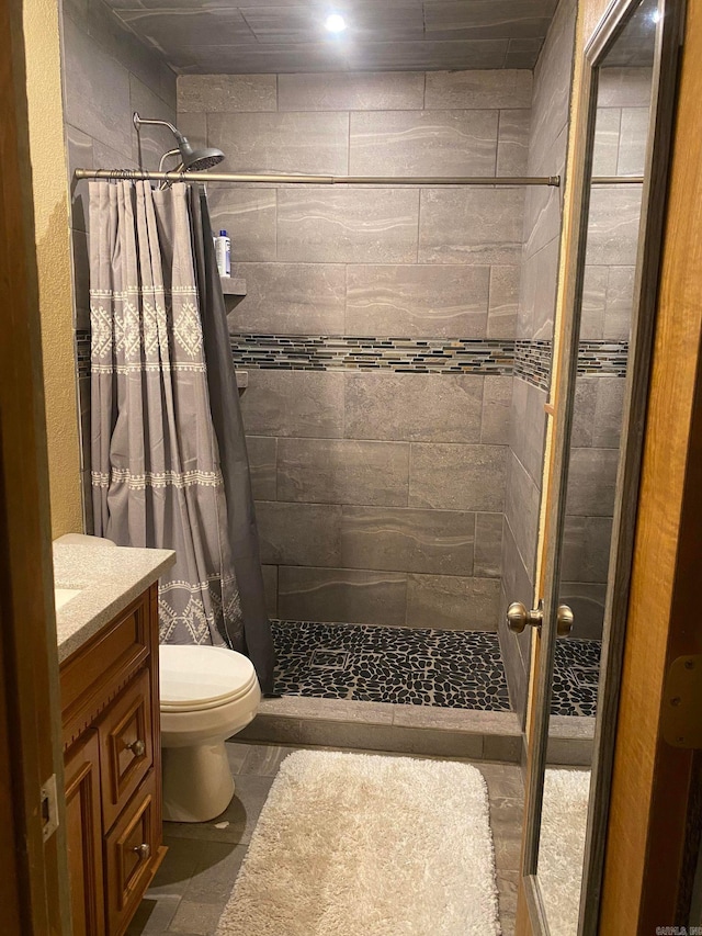 bathroom with a shower with shower curtain, vanity, toilet, and tile flooring