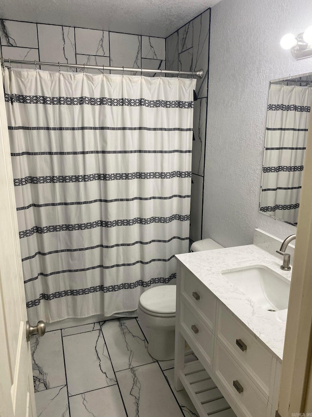 bathroom with tile flooring, vanity with extensive cabinet space, toilet, and a textured ceiling