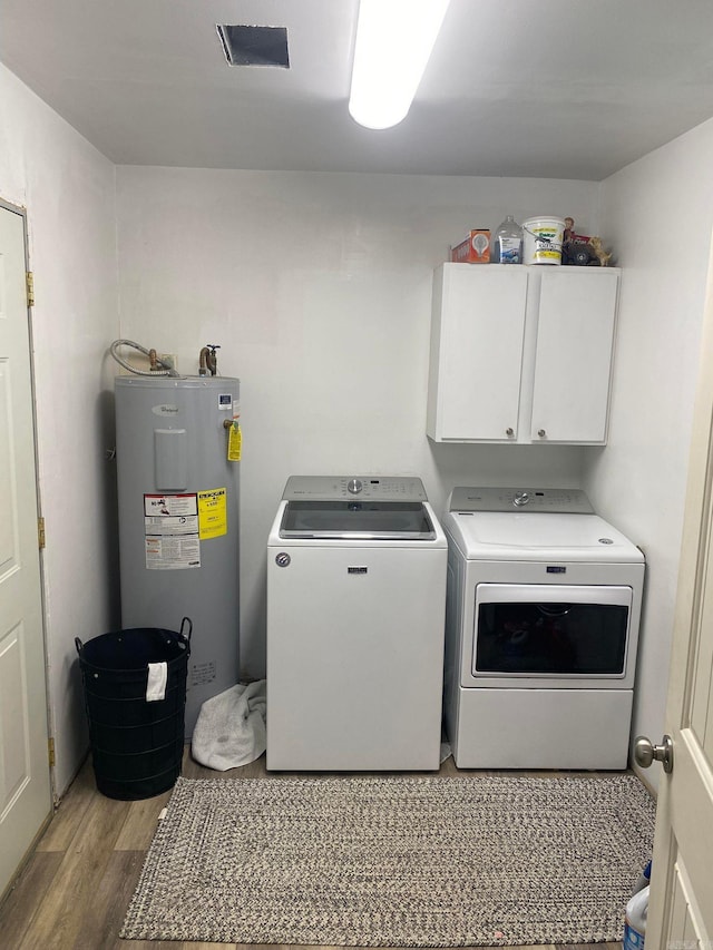 laundry area with light hardwood / wood-style flooring, water heater, cabinets, and washer and clothes dryer