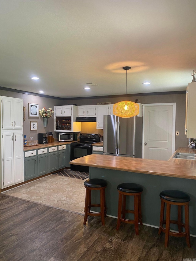 kitchen with stainless steel appliances, white cabinets, sink, and decorative light fixtures