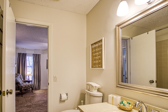 bathroom featuring a textured ceiling, vanity, and toilet