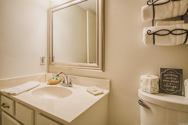 bathroom with vanity, toilet, and a textured ceiling