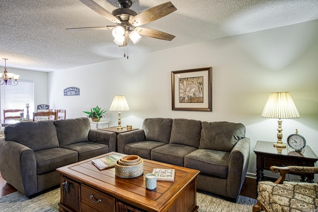 living room featuring ceiling fan with notable chandelier and a textured ceiling