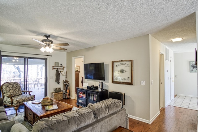 living room featuring tile flooring, ceiling fan, and a textured ceiling