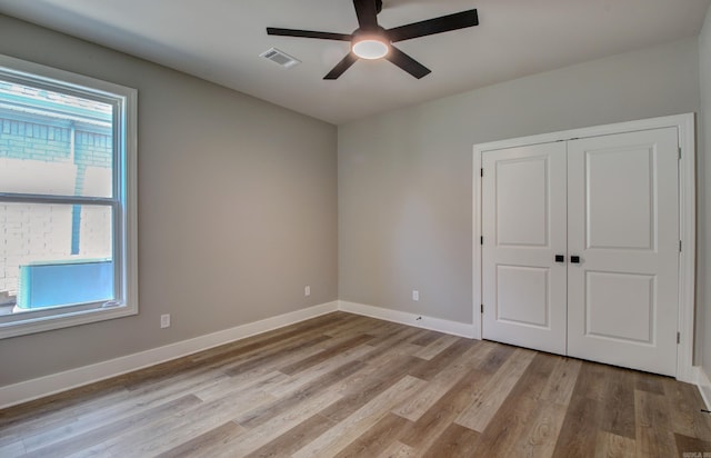 unfurnished bedroom with light wood-type flooring, multiple windows, ceiling fan, and a closet