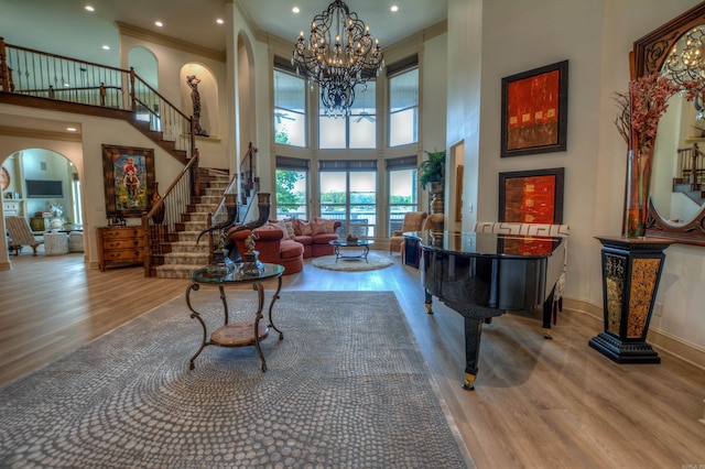 interior space featuring a notable chandelier, a high ceiling, crown molding, and hardwood / wood-style flooring