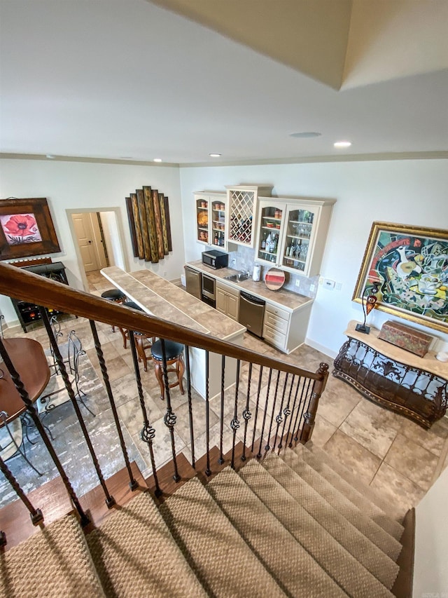 stairs featuring crown molding, sink, and light tile flooring