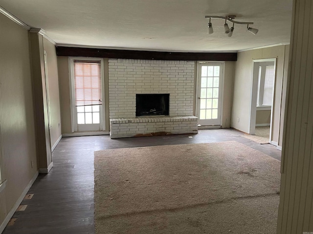 unfurnished living room featuring wood-type flooring, crown molding, track lighting, and a brick fireplace