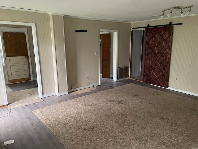 unfurnished room with wood-type flooring, a barn door, and track lighting