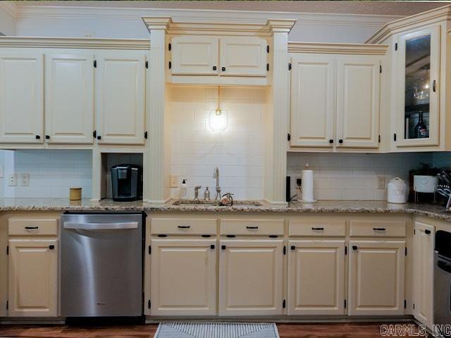 kitchen with stainless steel dishwasher, sink, tasteful backsplash, and cream cabinetry