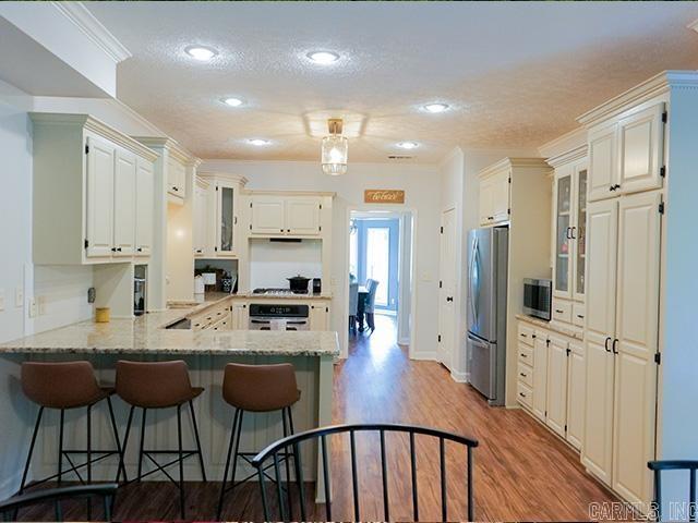 kitchen featuring appliances with stainless steel finishes, a breakfast bar area, light hardwood / wood-style flooring, kitchen peninsula, and light stone countertops