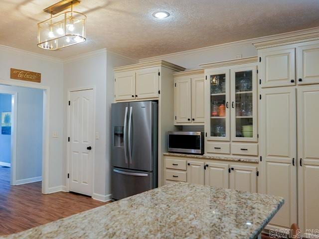 kitchen featuring hanging light fixtures, crown molding, hardwood / wood-style floors, stainless steel appliances, and light stone counters