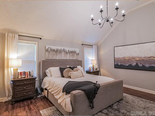 bedroom with dark hardwood / wood-style floors, crown molding, a chandelier, and lofted ceiling