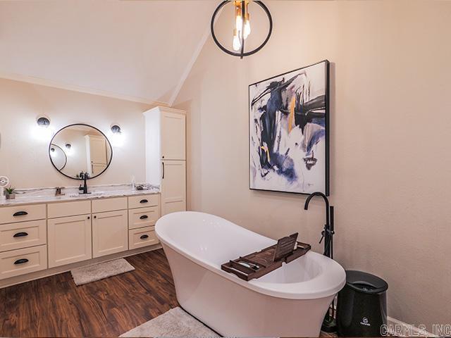 bathroom with crown molding, wood-type flooring, vanity, and a bath