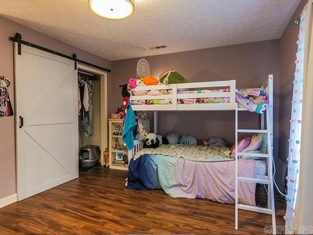 bedroom with hardwood / wood-style flooring, a barn door, and a textured ceiling