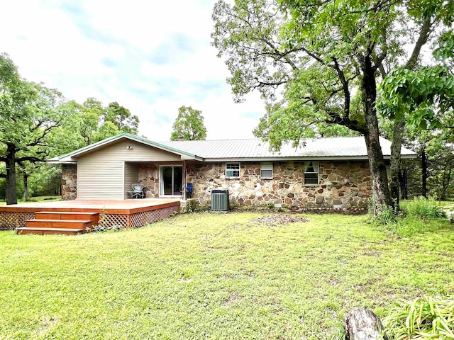 rear view of property featuring a yard, a wooden deck, and central AC