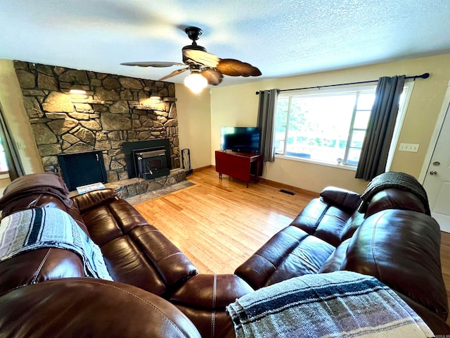 living room with ceiling fan, hardwood / wood-style flooring, a fireplace, and a textured ceiling