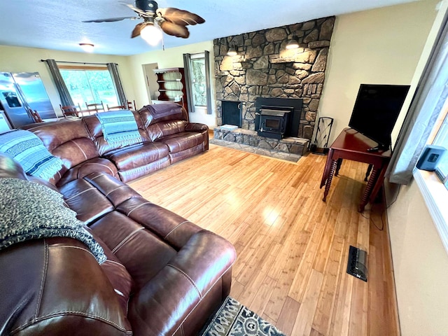 living room featuring hardwood / wood-style floors, ceiling fan, a fireplace, and a textured ceiling