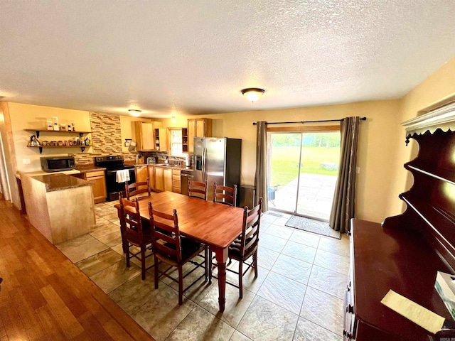 dining area featuring a textured ceiling, sink, and light hardwood / wood-style floors