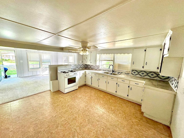 kitchen featuring plenty of natural light, white gas range oven, ceiling fan, and sink