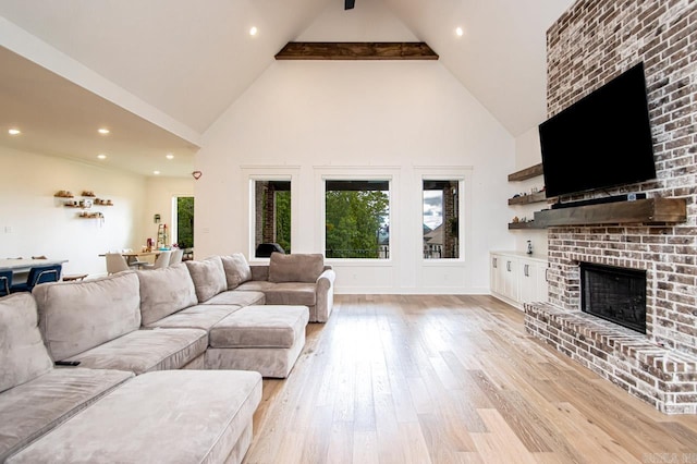 living room with a brick fireplace, light wood-type flooring, beamed ceiling, and high vaulted ceiling