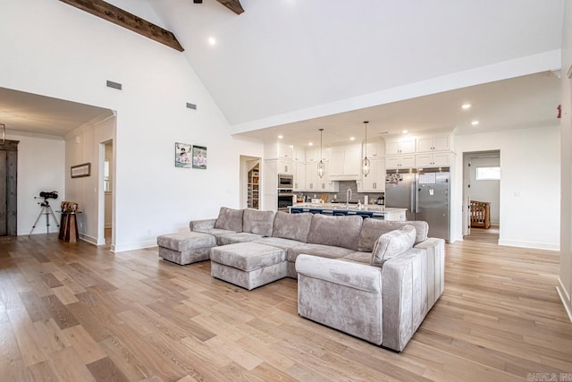 living room with beamed ceiling, sink, light hardwood / wood-style flooring, and high vaulted ceiling