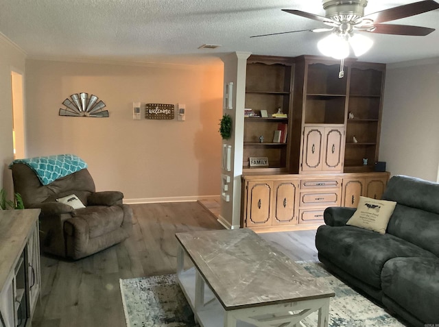 living room featuring ornamental molding, ceiling fan, dark hardwood / wood-style floors, and a textured ceiling