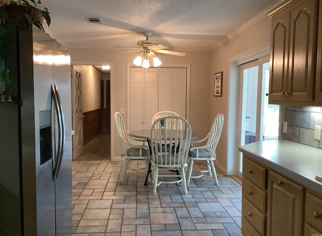 unfurnished dining area with a textured ceiling, ceiling fan, light tile flooring, and ornamental molding