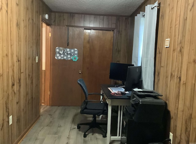 office area featuring wood walls, light hardwood / wood-style floors, and a textured ceiling