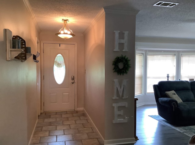 entryway featuring ornamental molding, tile floors, and a textured ceiling