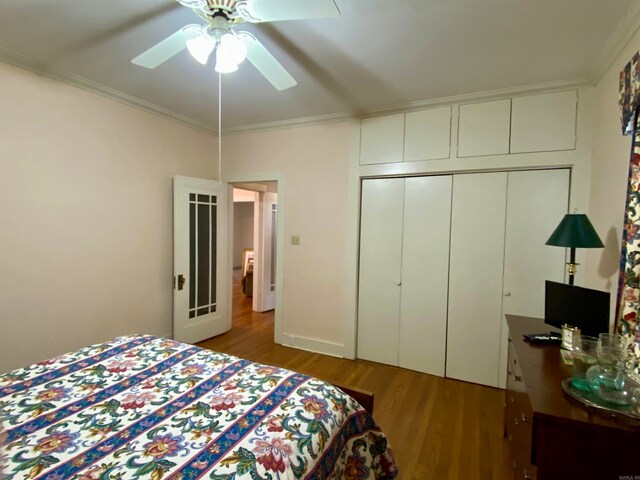 bedroom featuring ornamental molding, wood-type flooring, ceiling fan, and a closet