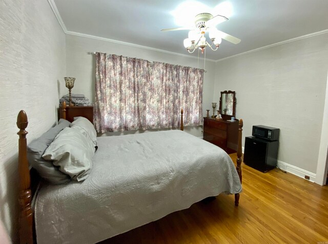 bedroom featuring wood-type flooring, ornamental molding, and ceiling fan